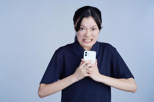 スマホをもって憤慨する女性 女性,スマートフォン,持つの写真素材