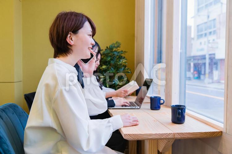 カフェの窓際カウンター席にいる女性（スマホ・笑顔） スマートフォン,スマホ,電話の写真素材
