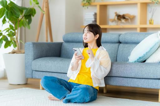 部屋でスマホを操作する若い女性 部屋でスマホを操作する若い女性 スマホ,若い女性,笑顔の写真素材