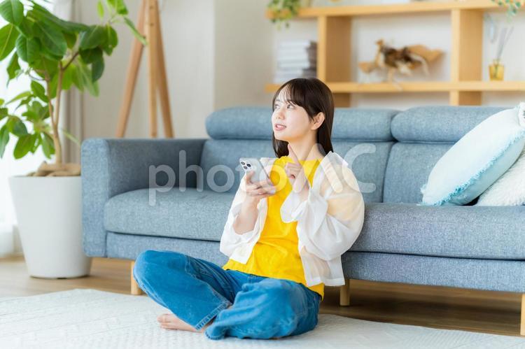 部屋でスマホを操作する若い女性 スマホ,若い女性,笑顔の写真素材