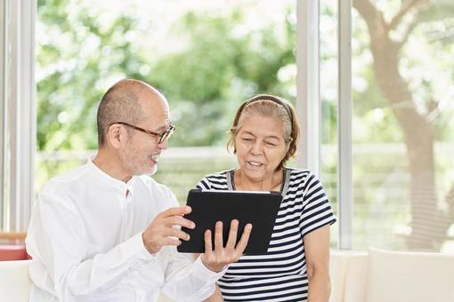 Elderly couple looking at a tablet with a smile, senior citizens, couple, tablet, JPG