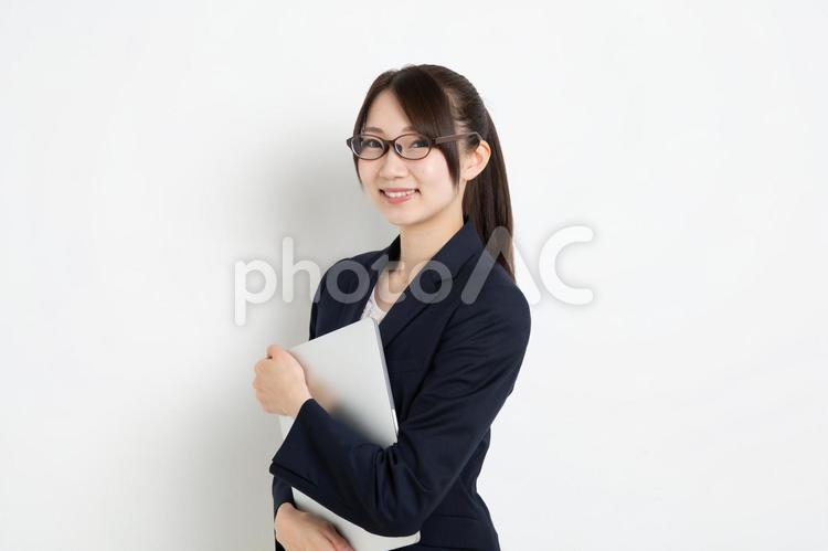 パソコンを抱えているメガネのビジネスウーマン 女,女性,日本人の写真素材