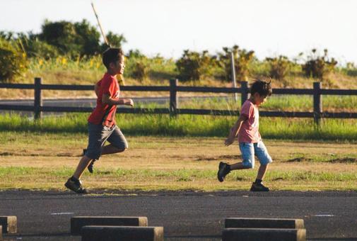 <素材>夏の夕暮れの公園で元気に遊ぶ兄弟 <素材>夏の夕暮れの公園で元気に遊ぶ兄弟の写真