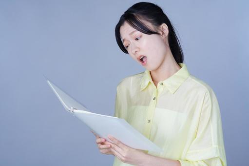 本を見る黄色い服の女性 女性,バインダー,ファイルの写真素材