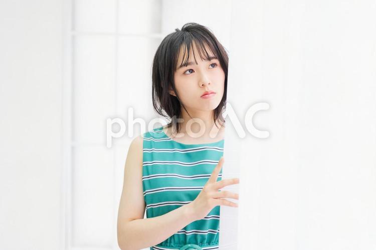 窓際に立ってこちらを見つめている若い女性 窓際,立つ,若いの写真素材