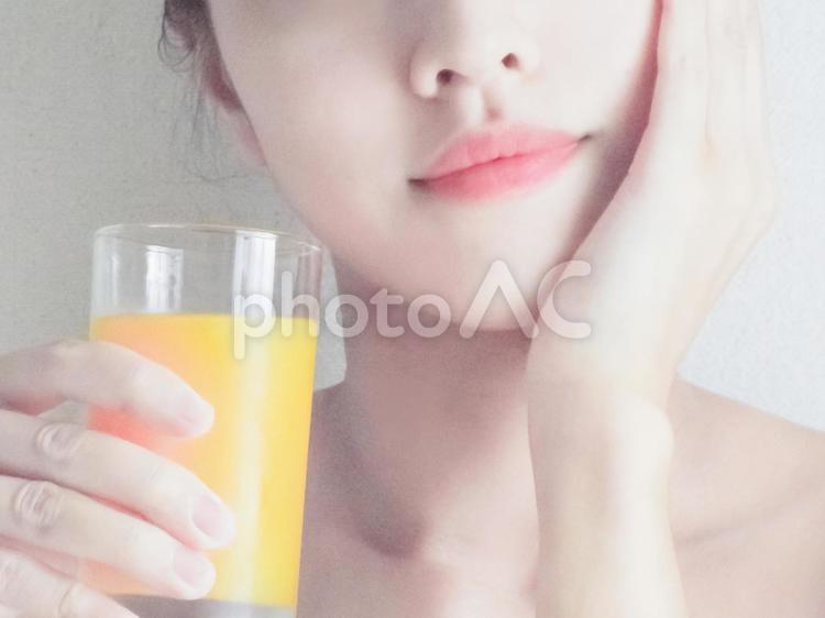 ジュースを持って顔を撫でる女性 女性,スキンケア,手の写真素材