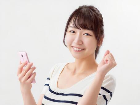 Image of a woman holding a smartphone and doing a guts pose Image of a woman holding a smartphone and doing a guts pose