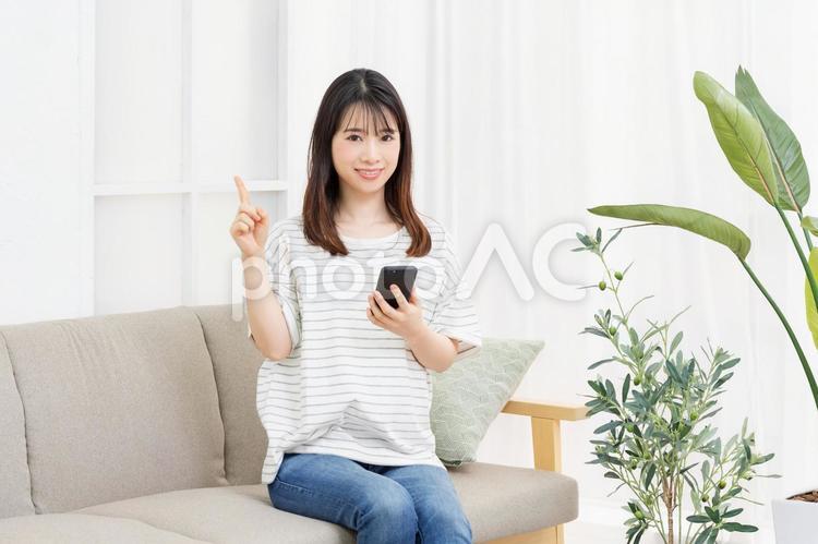 部屋のソファーに座ってスマホを操作する若い女性 コピースペース,携帯,電話の写真素材