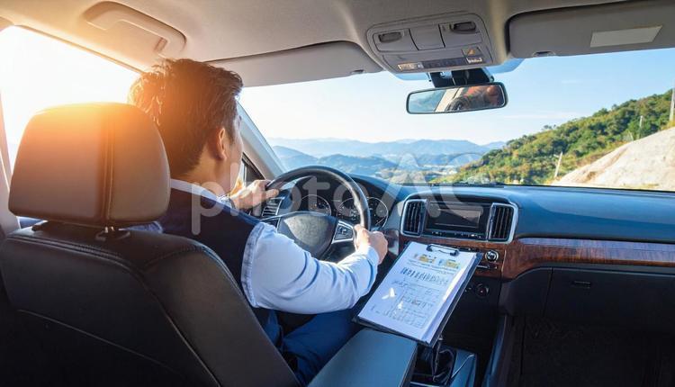 手もとに書類を持って運転するサラリーマン サラリーマン,ドライバー,営業マンの写真素材