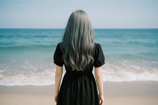 ビーチに立つグレーの髪の女性の写真