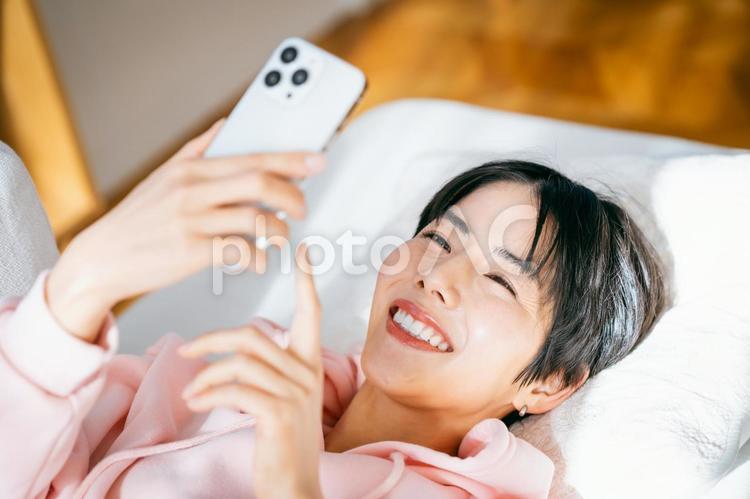  部屋でスマホを操作する若い女性 女性,スマホ,スマートフォンの写真素材