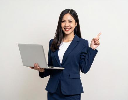 ノートパソコンを持ち案内する会社員女性 ノートパソコンを持ち案内する会社員女性の写真