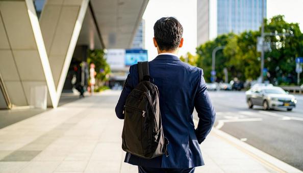 街中を通勤で歩いていくリュック姿の男性 街中を通勤で歩いていくリュック姿の男性の写真