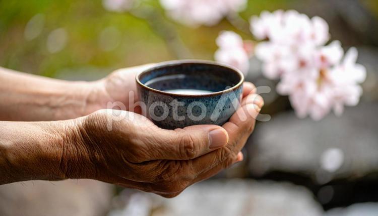 一杯の飲み物を手に取る日本人男性の手 花見,水,飲料水の写真素材