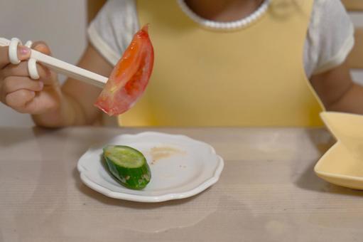 トレーニング箸で野菜を食べる子ども トレーニング箸で野菜を食べる子どもの写真
