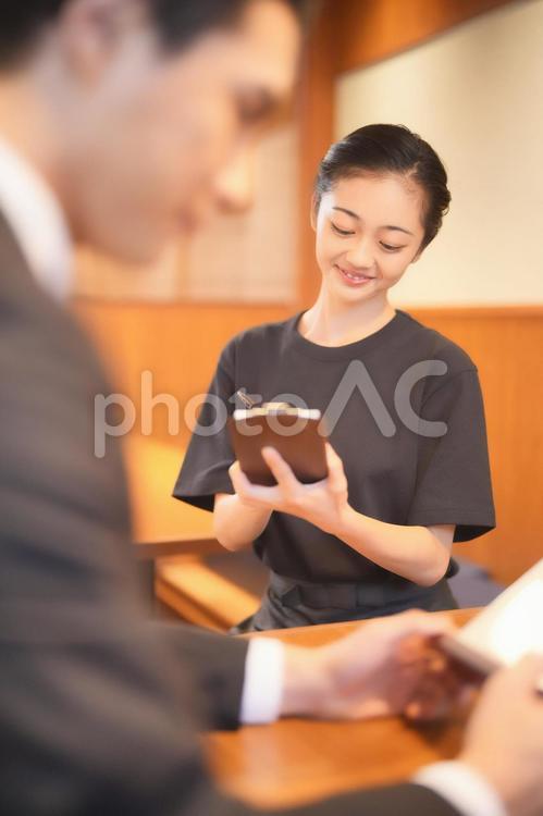 男性客から注文を取る女性店員（縦） 女性,男女,大学生の写真素材