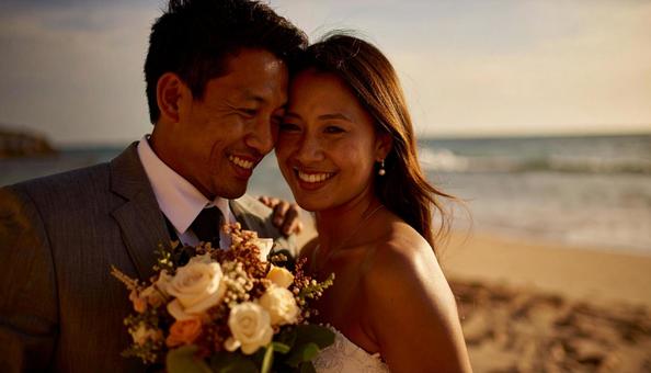 海辺でブーケを持ち顔を見合わせる新郎新婦 海辺でブーケを持ち顔を見合わせる新郎新婦の写真