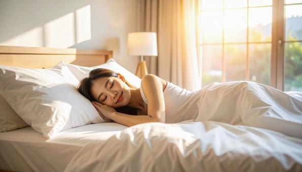 柔らかい光に包まれ寝室で眠る日本人女性 柔らかい光に包まれ寝室で眠る日本人女性の写真