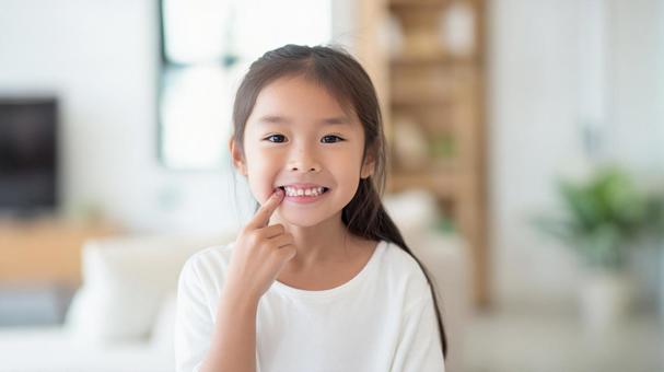 歯を指差している女の子 歯を指差している女の子の写真