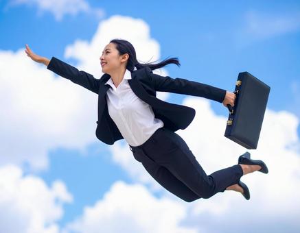 青空の中ジャンプするスーツを着た女性 青空の中ジャンプするスーツを着た女性の写真
