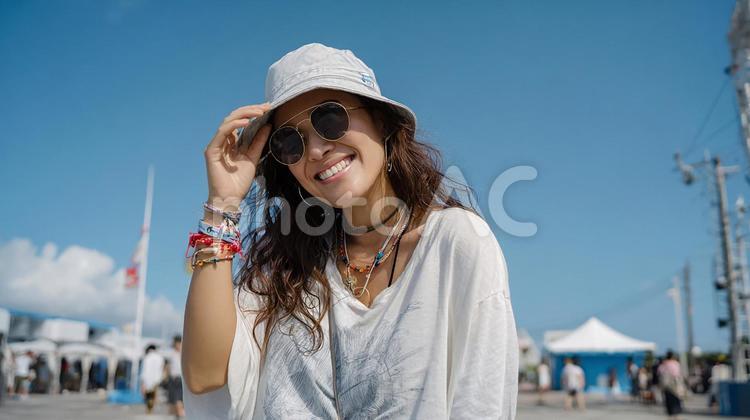 青空の下、眩しそうに微笑む若い女性 女性,日本人,夏の写真素材