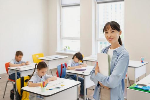 腕を組んでカメラ目線の先生と勉強する生徒たち 女性,女の子,男の子の写真素材
