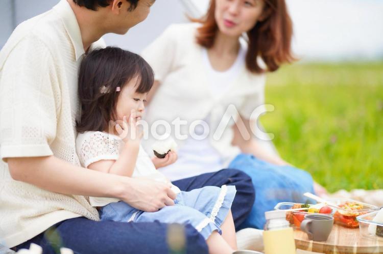 おにぎりを持っている女の子と話す男性と女性 女性,男性,女の子の写真素材