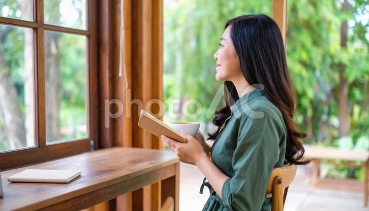 本とコーヒーカップを手にくつろぐ女性 カフェ,読書,自己啓発の写真素材