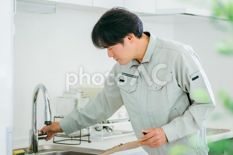 キッチンと作業着姿の男性（水道） 水道屋,水漏れ,漏水の写真素材