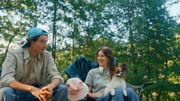 森の中でリラックスする二人 男女,外国人,犬の写真素材