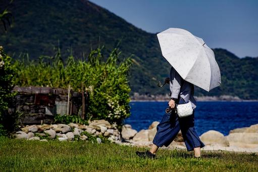 <素材>旅行で夏の海辺を散策する女性 <素材>旅行で夏の海辺を散策する女性 女性,散歩,歩くの写真素材