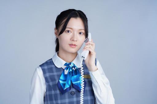 制服姿の女性が電話を取る 女性,真顔,電話の写真素材