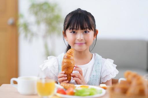 パンを口に運ぶ少女 女の子,食事,クロワッサンの写真素材