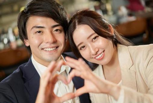 Asian couple making a heart symbol with their fingers Asian couple making a heart symbol with their fingers