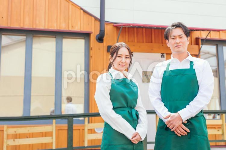 お店の前に立つエプロン姿の男女 カフェ,飲食店,ウェイトレスの写真素材