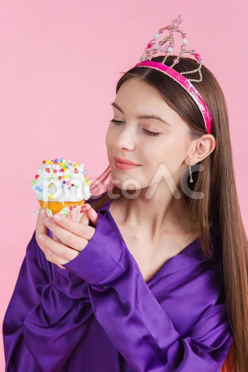 ティアラを付けたカップケーキを持っている女性 ケーキ,スイーツ,デザートの写真素材