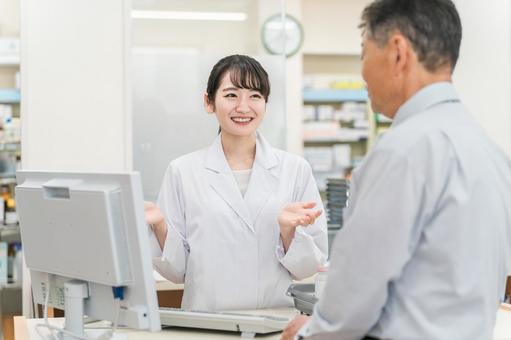 薬局でシニア患者に説明する薬剤師の女性 薬局でシニア患者に説明する薬剤師の女性 薬局,薬剤師,服薬指導の写真素材