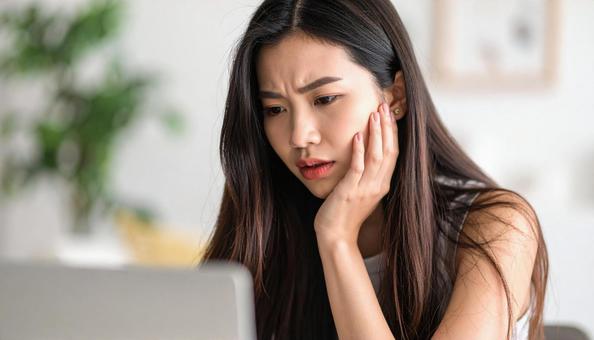 パソコン画面を見て悩む若い女性 パソコン画面を見て悩む若い女性の写真