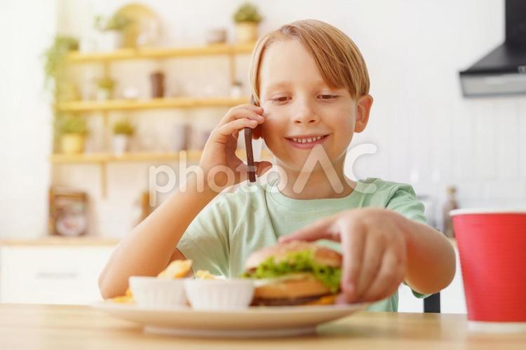 ハンバーガーを掴んで電話する男の子と太陽 男の子,人物,飲むの写真素材