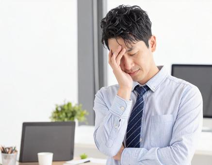 頭を抱えて頭痛に悩む男性 頭を抱えて頭痛に悩む男性の写真