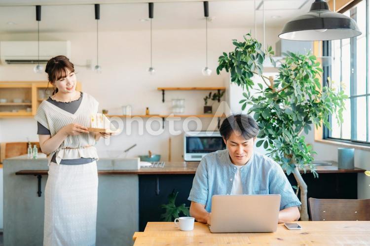 テレワークする男性と食事を運ぶ女性 ランチ,テレワーク,昼食の写真素材