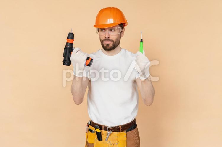 手に持った工具を見るヘルメットの男性 男性,電動工具,持つの写真素材