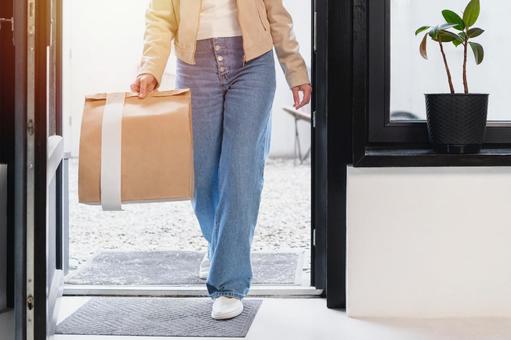 置き配された紙袋を持って歩く女性 配達,フードデリバリー,デリバリーの写真素材