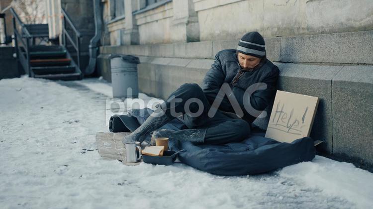 もたれて寝るホームレスの男性 男性,ニット帽,ヒゲの写真素材