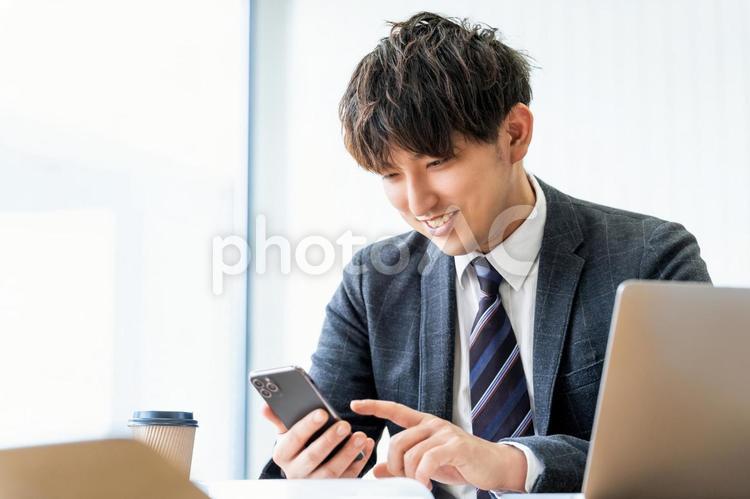 スマホを使う笑顔の男性ビジネスマン 男性,ビジネス,ビジネスマンの写真素材
