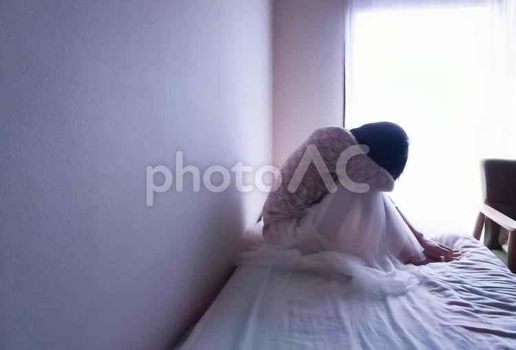 ベッドの上でうずくまる女性(横長) 女性,休む,悩むの写真素材