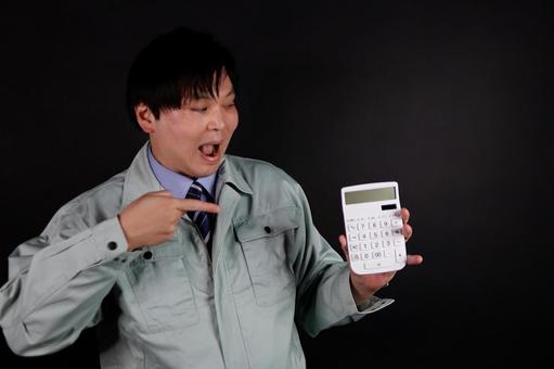 電卓を指差す作業着の男性 電卓を指差す作業着の男性の写真