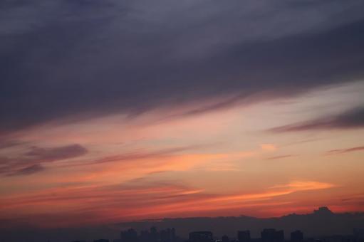 茜色の夕空とシルエットの街並みの風景 茜色の夕空とシルエットの街並みの風景の写真