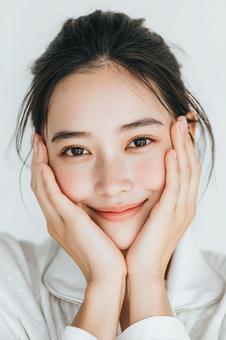頬に手を添えて微笑む女性のクローズアップ 頬に手を添えて微笑む女性のクローズアップの写真