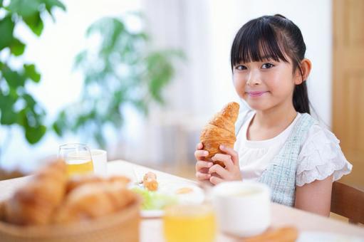 食卓で笑顔を見せる少女の朝ごはんシーンの写真